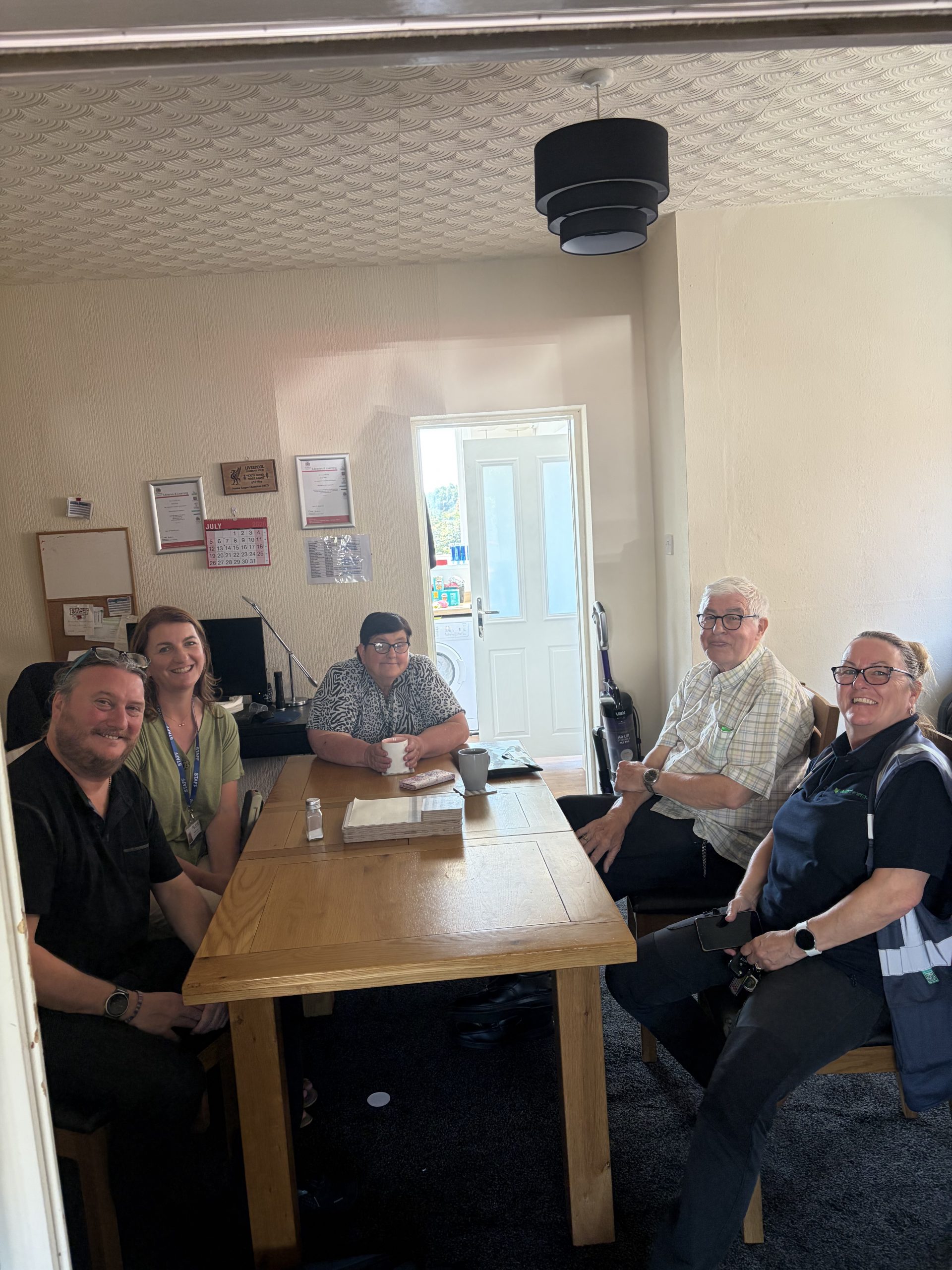 Five people sat around a table, two are Danielle and Alan from Alt Valley Community Trust, one is Ann from Verdant Energy and two are housing tenants.